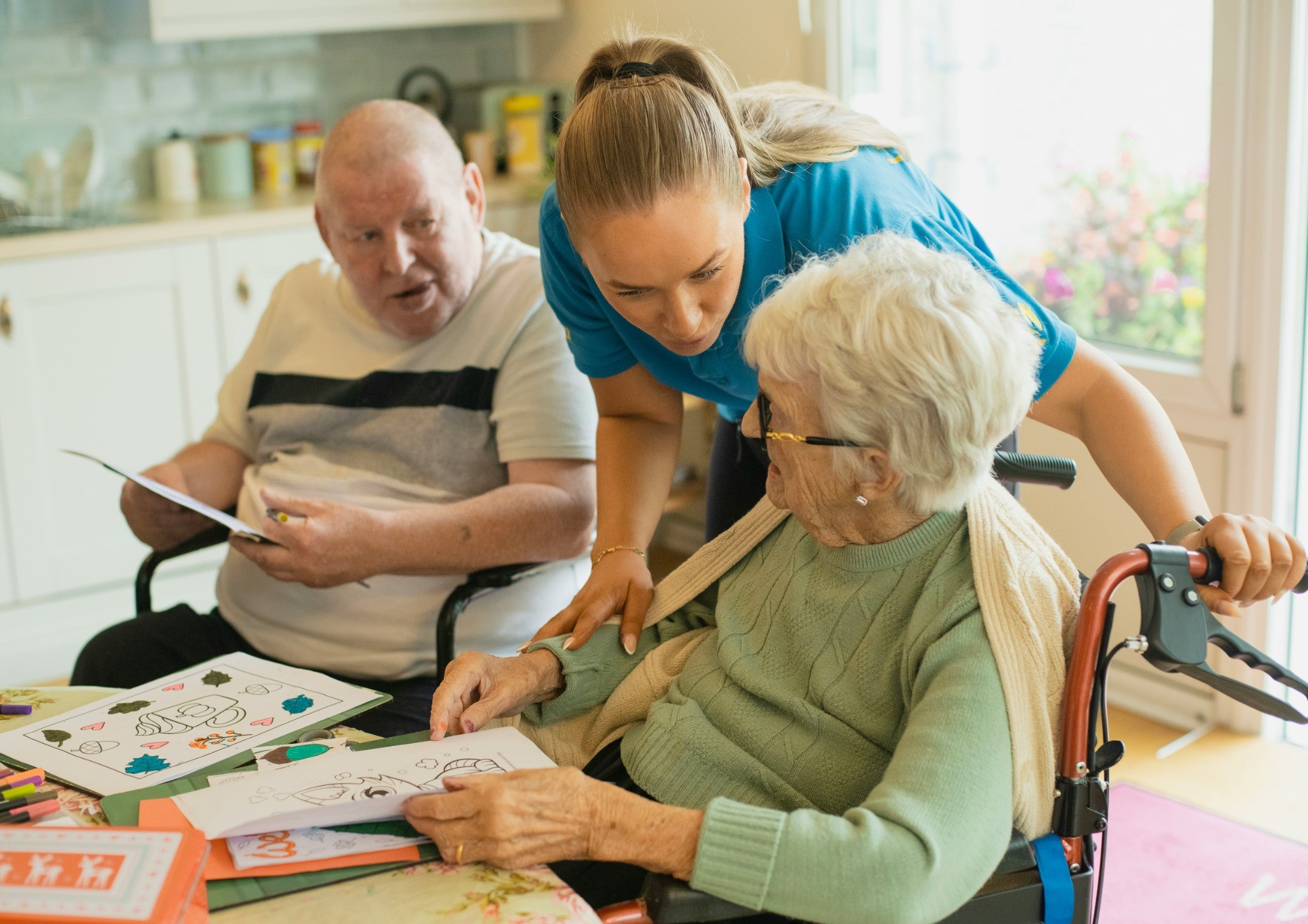 Aged care nurse assisting elderly residents with activities in a care home.
